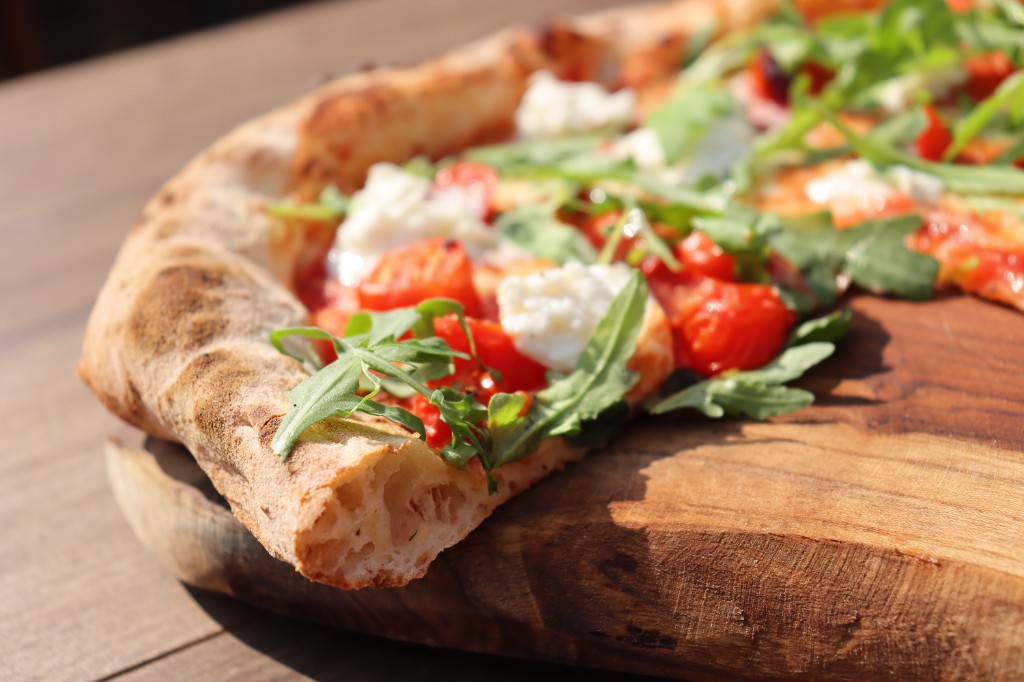 Verse pizza met rucola op een houten plank